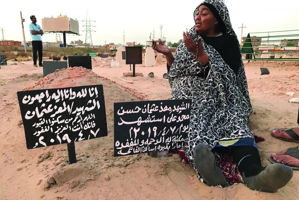 TOPSHOT - Khadom, the mother of Al-Moez visits the tomb of her son, killed when a bullet pierced the window of his workplace and lodged itself in his heart during an anti-government demonstration in the Sudanese capital Khartoum in April, on July 9, 2019. - Like dozens of others who lost a son, uncle or brother, Al-Moez' family has paid a high price for Sudan's revolution that toppled its longtime autocratic ruler Omar al-Bashir in April. (Photo by Claire DOYEN / AFP)